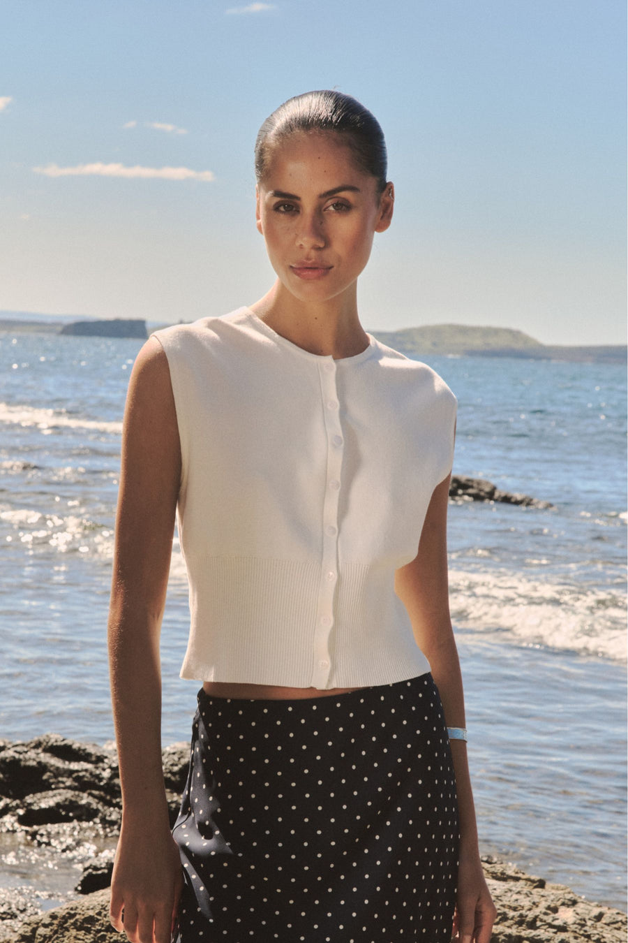 Faye Sleeveless Button Up Knit in ivory, front view worn with a black spot-print skirt